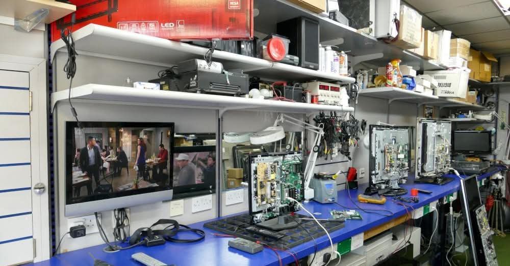 Electronics repair workbench with televisions and test equipment