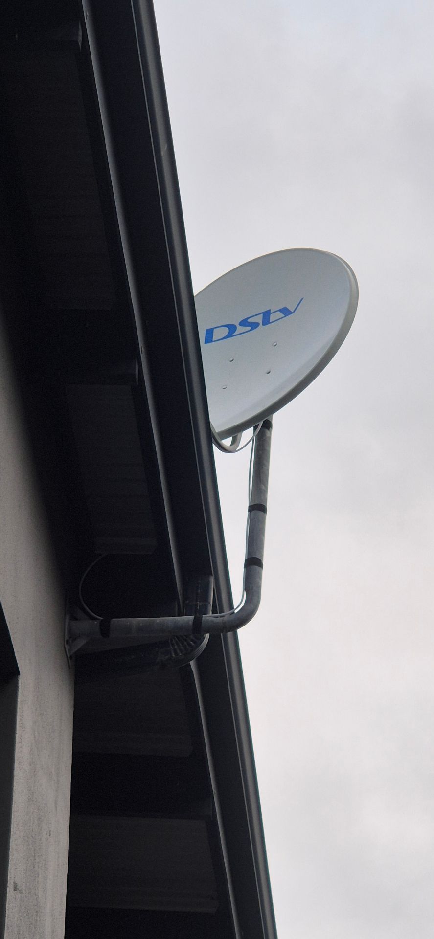 DStv satellite dish mounted under a roof fascia